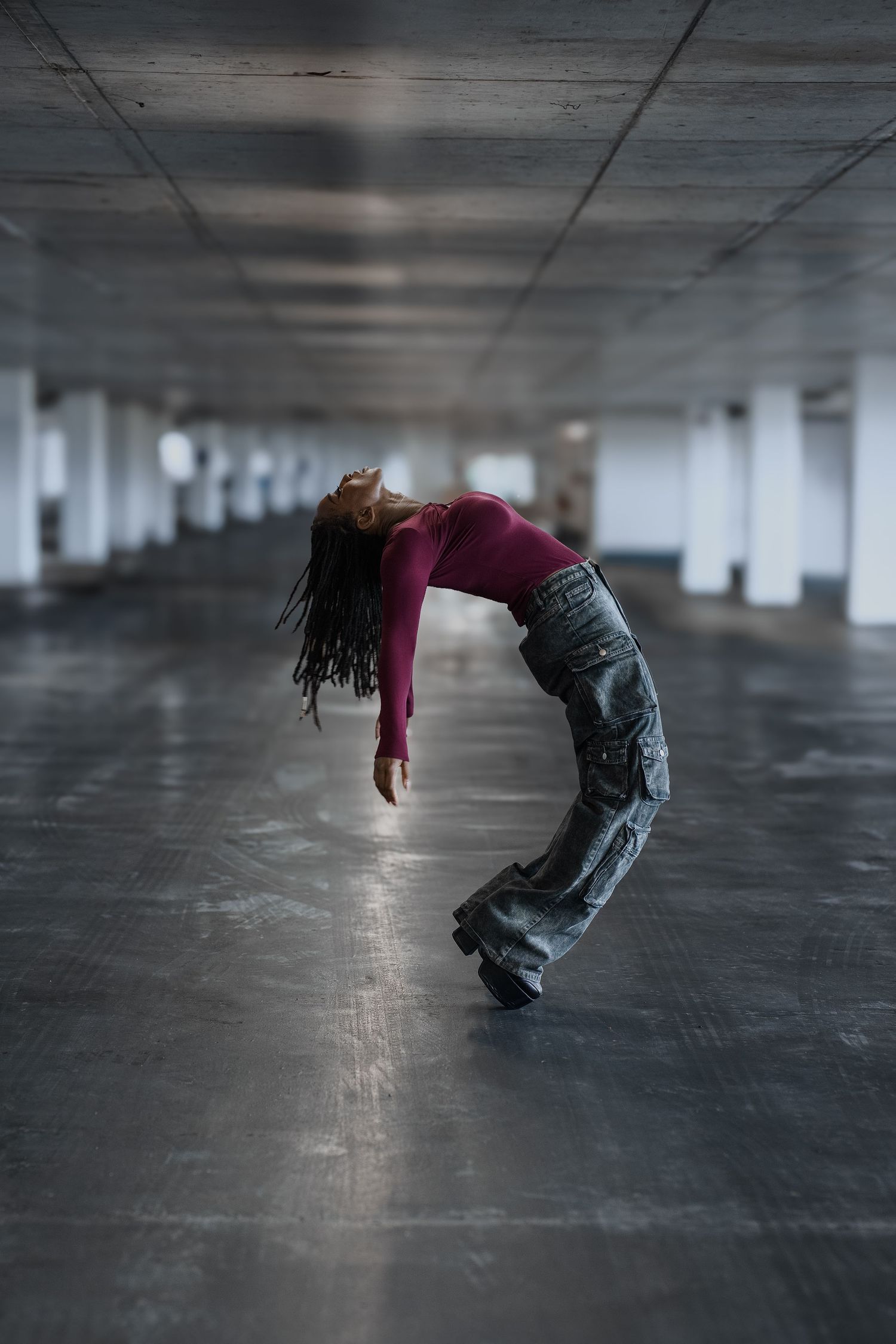 Jordan Frazier: Athletic dancer/actor performs a dramatic backbend in an empty urban parking garage with dramatic lighting and shadows.