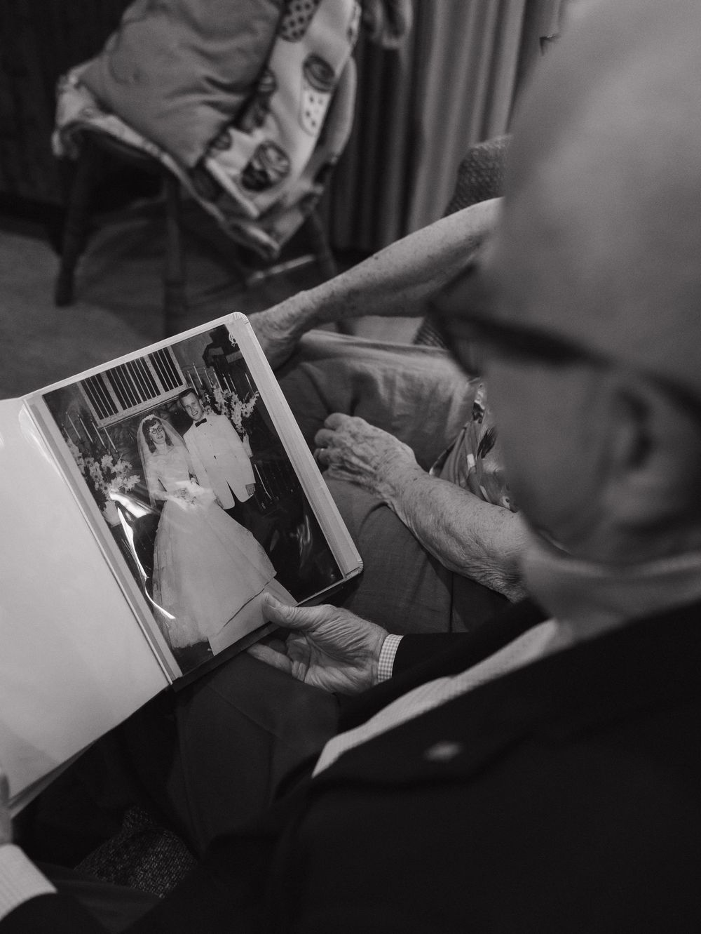 Someone looking through a photo album showing black and white photographs from what appears to be a wedding.