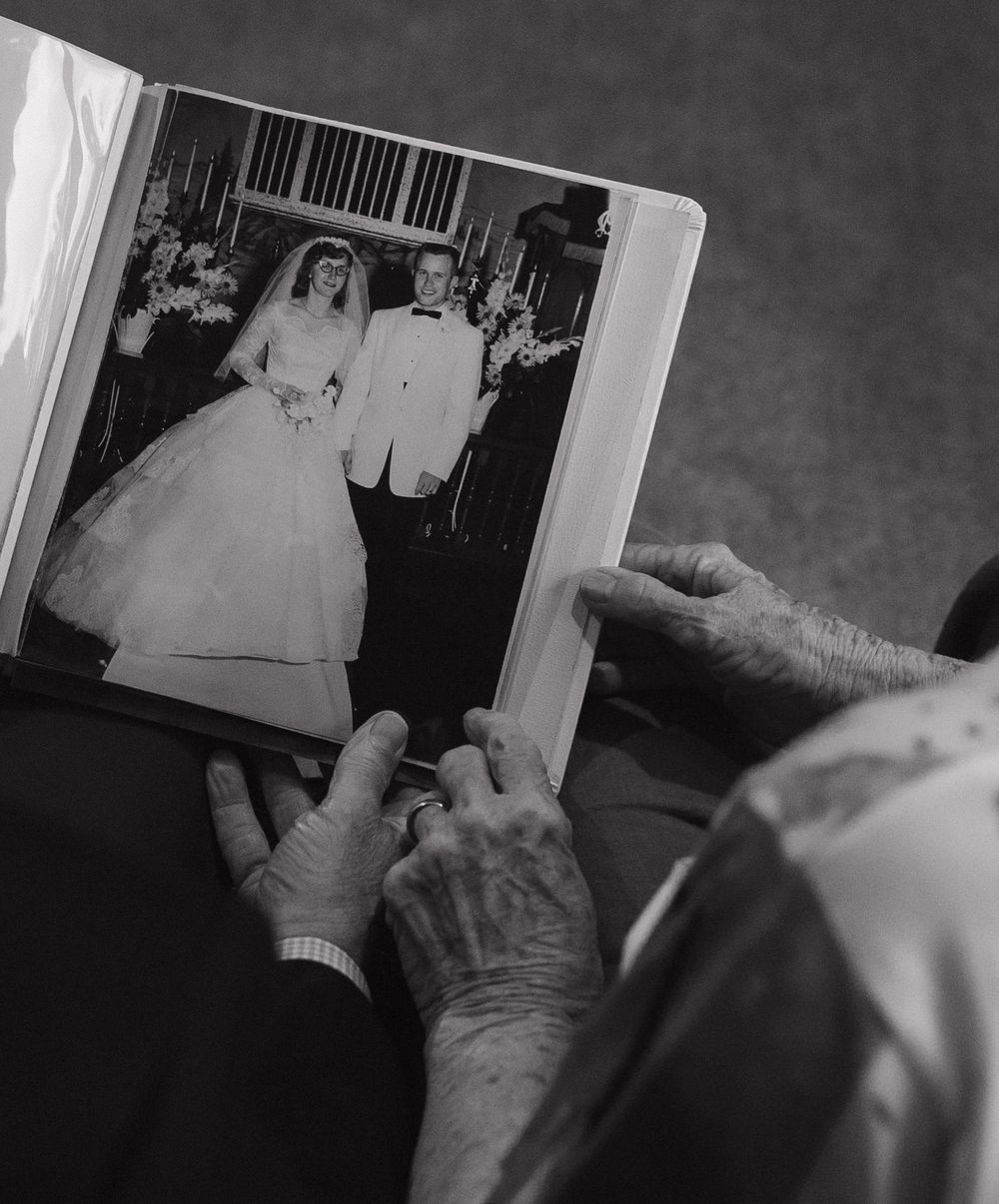 Hand flipping through pages of an old photo album showing black and white photographs in a nostalgic way.