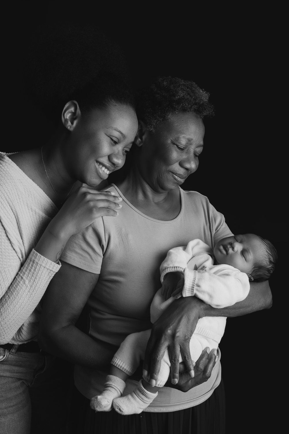 Touching black and white portrait of a multigenerational family moment with a newborn baby.