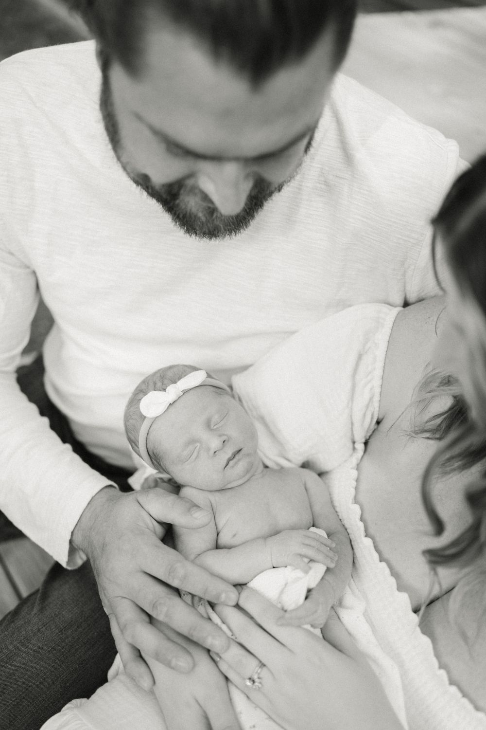Black and white portrait of newborn baby sleeping peacefully in gentle embrace.