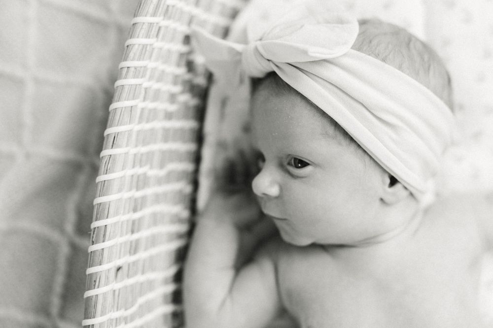 Close-up black and white portrait of a newborn baby wearing a soft headband.