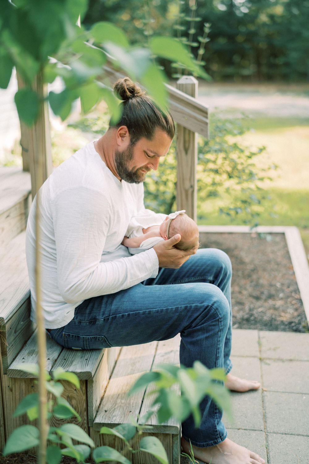 Parent sitting on wooden steps outdoors while tenderly holding a small baby.