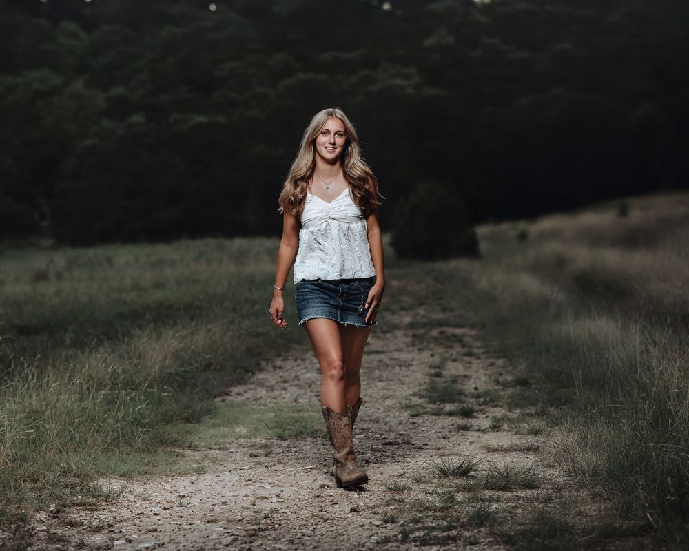 A candid walking shot from behind showing matching white outfits and boots on a country path.