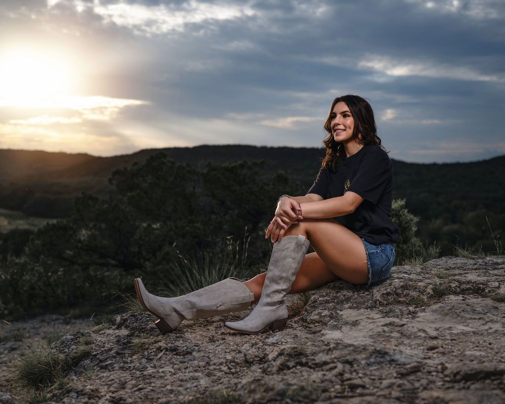 Cowboy boots and denim shorts create a country western look against a sunset mountain backdrop.