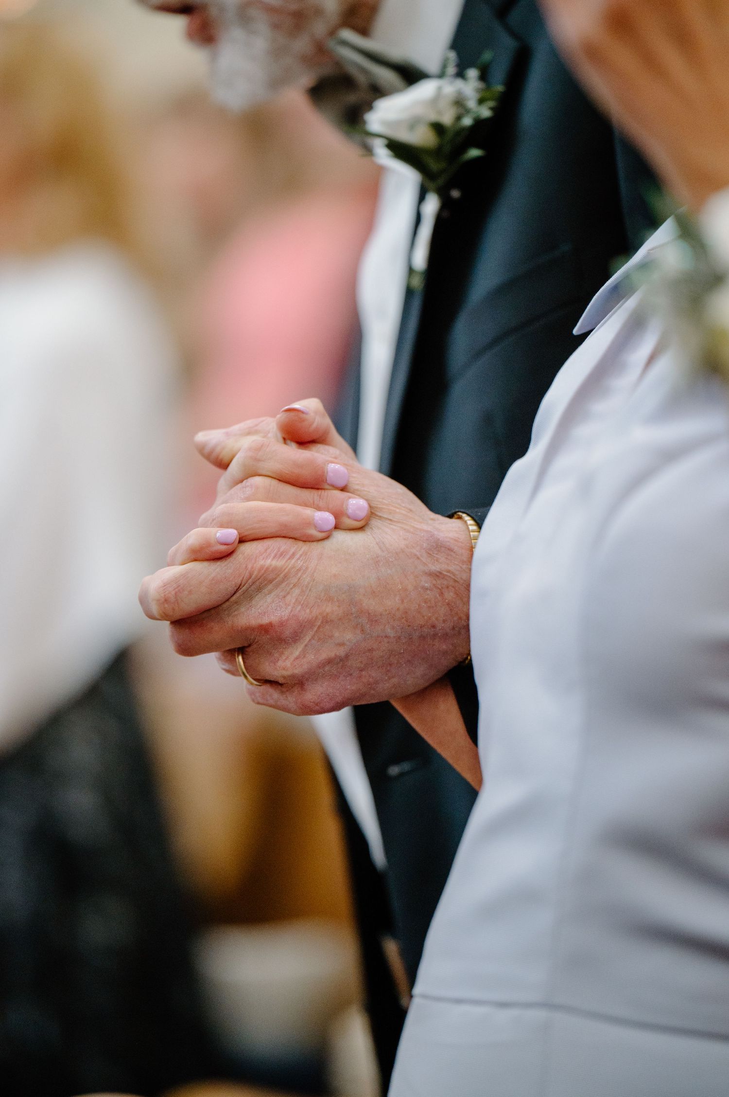 A close-up series of hands tenderly holding each other during what appears to be a wedding ceremony or formal event.