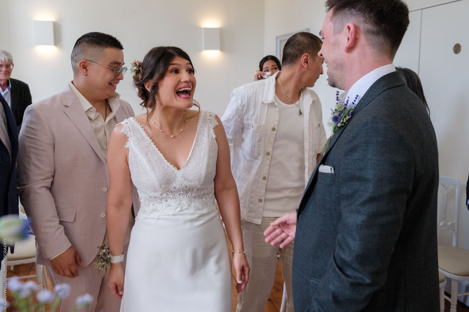 A candid moment of laughter and joy between people at a wedding celebration in a bright indoor venue.