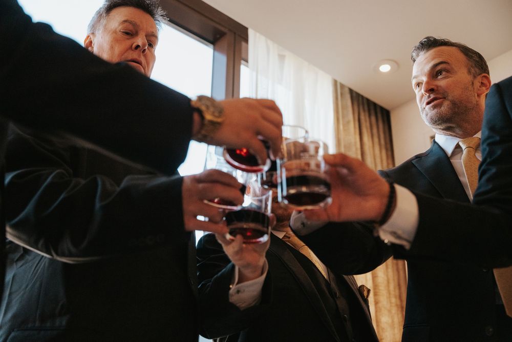 People in business attire raise their glasses in celebration during a gathering.
