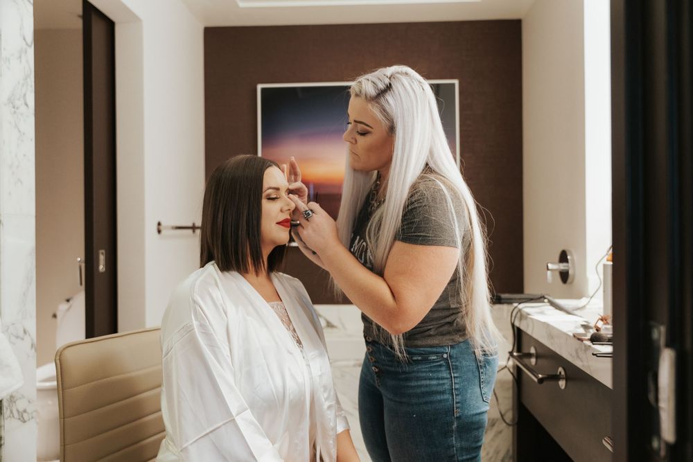 Two people stand in a bathroom getting ready together while taking their morning routine at the sink.