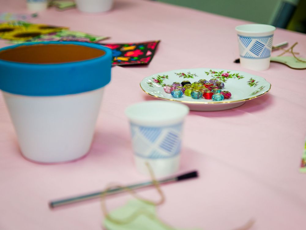 Close-up view of a pink party table setting with a blue-rimmed cup, decorative plate, and party supplies.
