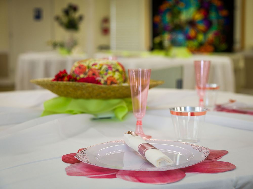 Table setting with pink flower-shaped placemats, plastic plates, and pink straws ready for a party celebration.