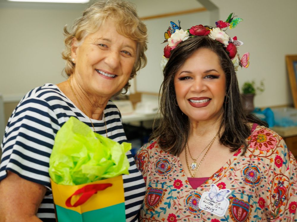 Two attendees at a festive tea party wearing colorful outfits and accessories.
