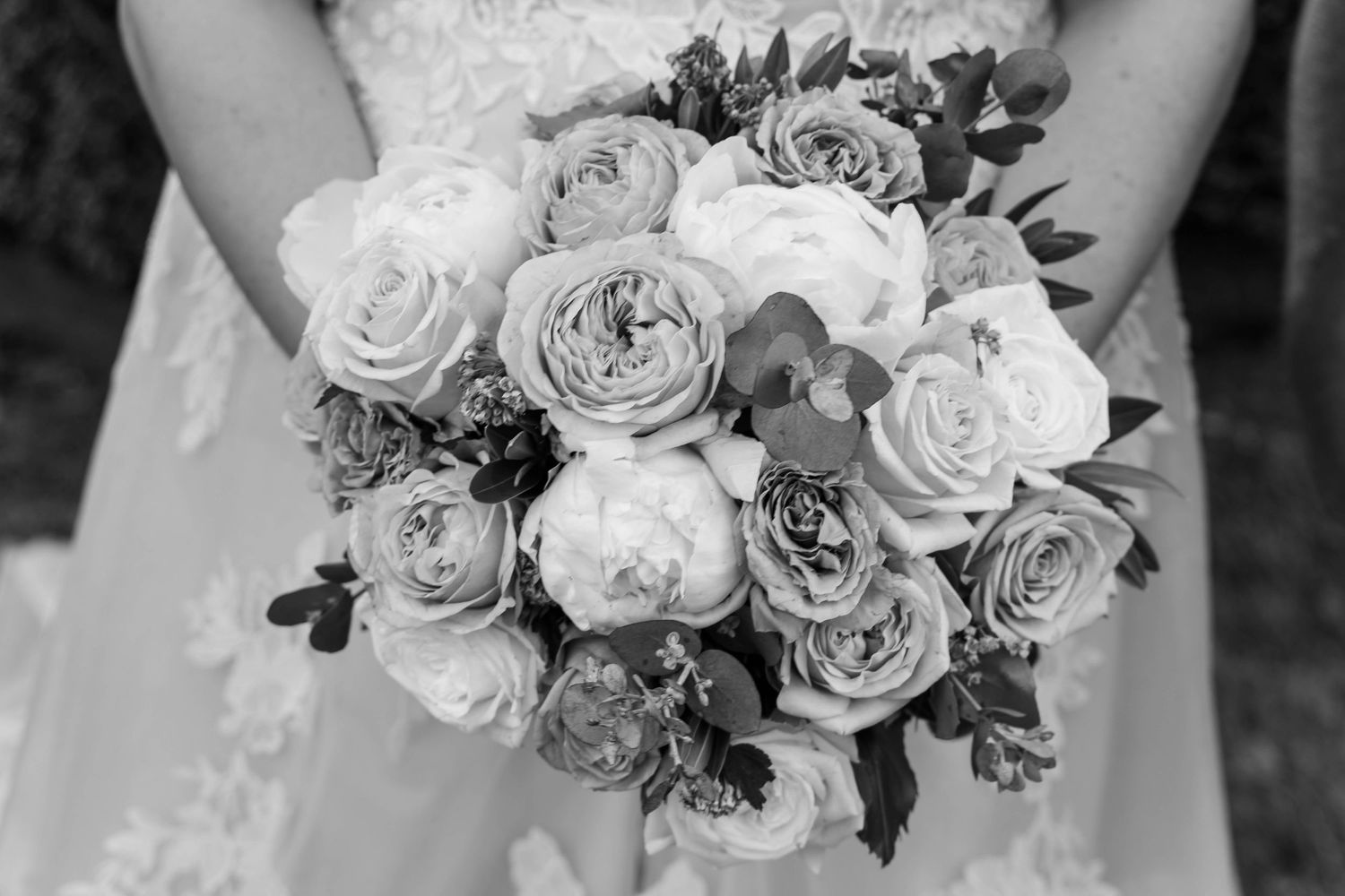 Black and white photo of an elegant bridal bouquet featuring roses and peonies in soft romantic arrangement.