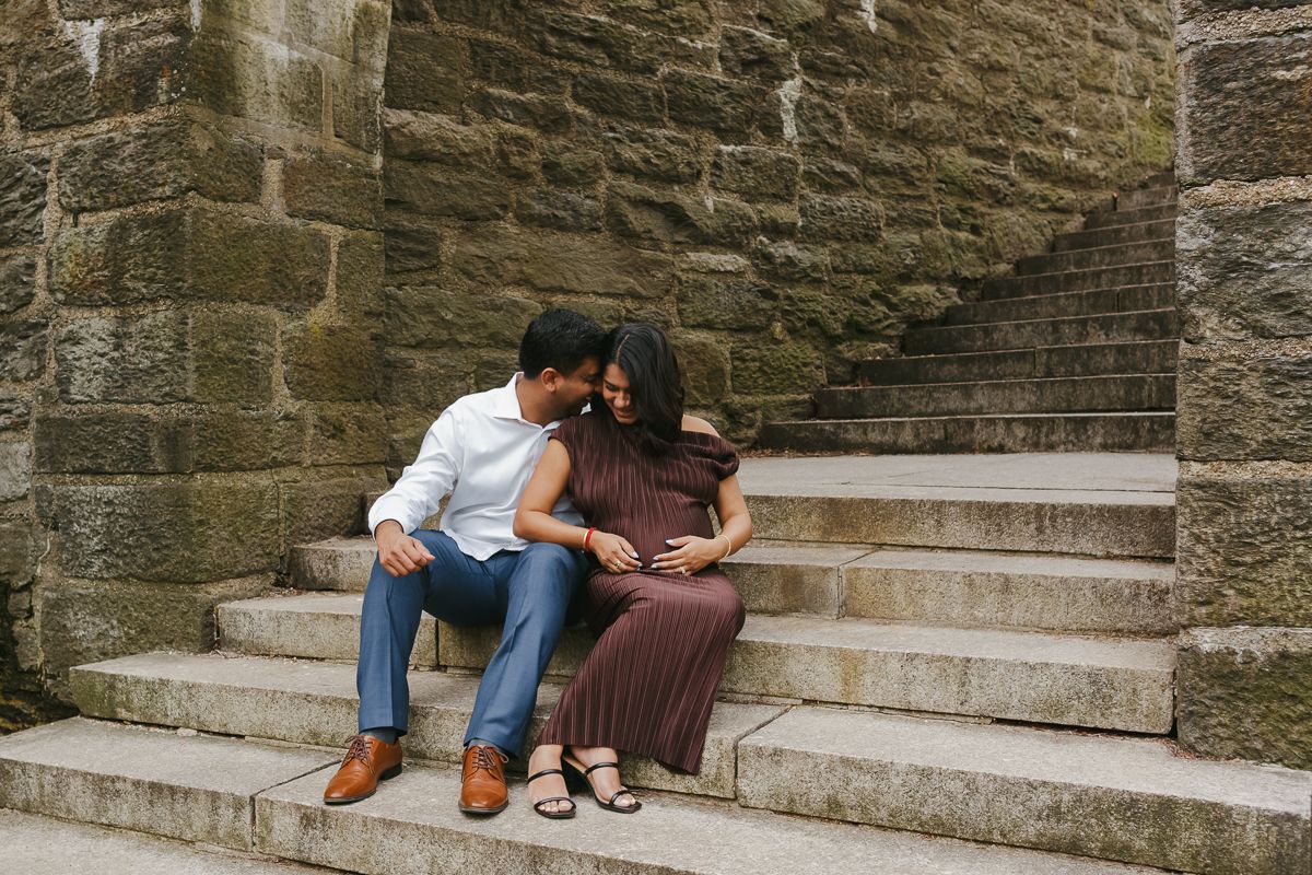Playful candid of expecting couple, surrounded by vibrant spring florals at Fort Tryon Park by NYC maternity Photographer Paula Brearley