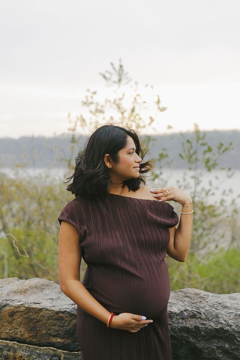 Elegant profile portrait of mom-to-be in a brown dress, framed by blooming spring flowers at Fort Tryon Park by Paula Brearley NYC maternity