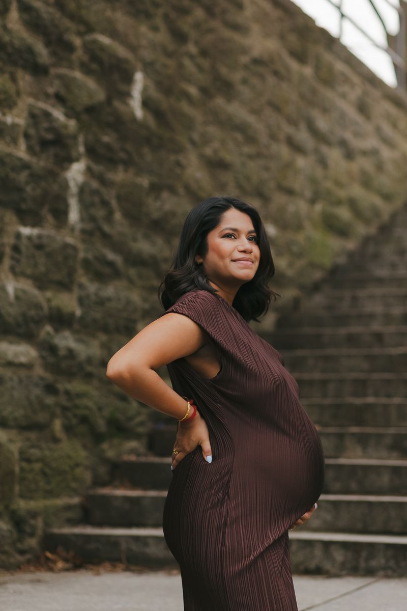 Intimate close-up of mom-to-be’s hands resting on her baby bump, capturing a heartfelt maternity moment in NYC by Paula Brearley maternity