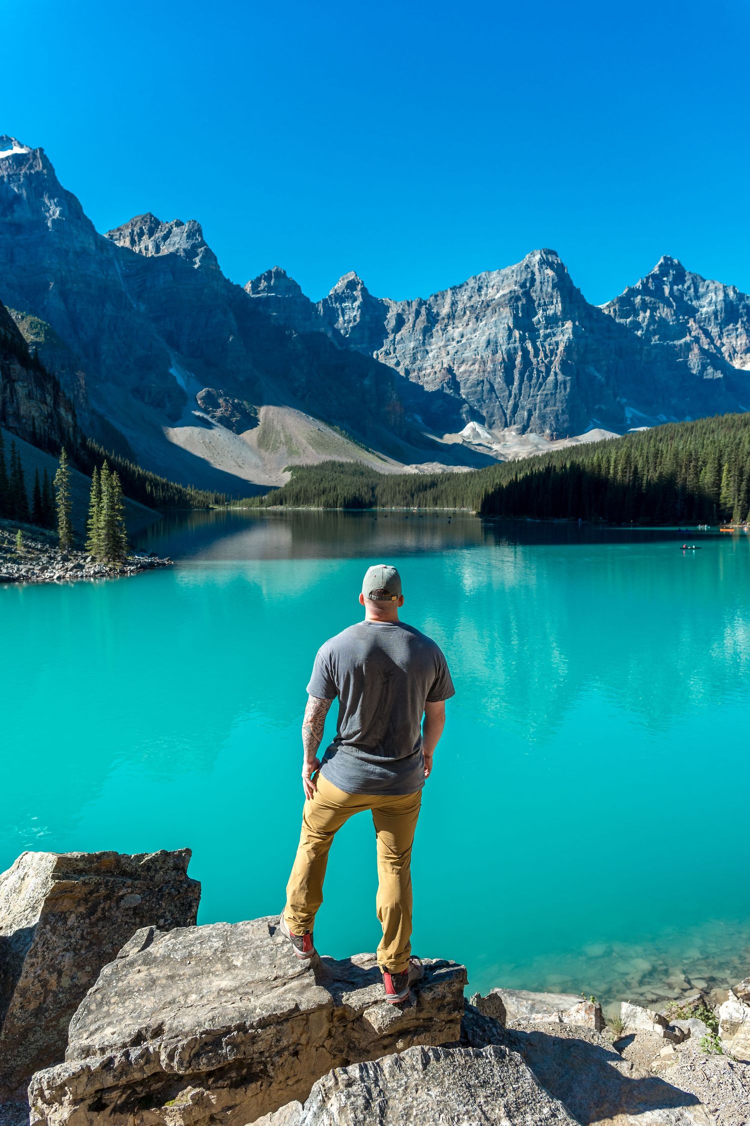Tourist admiring the turquoise waters of Moraine Lake with Valley of Ten Peaks backdrop.