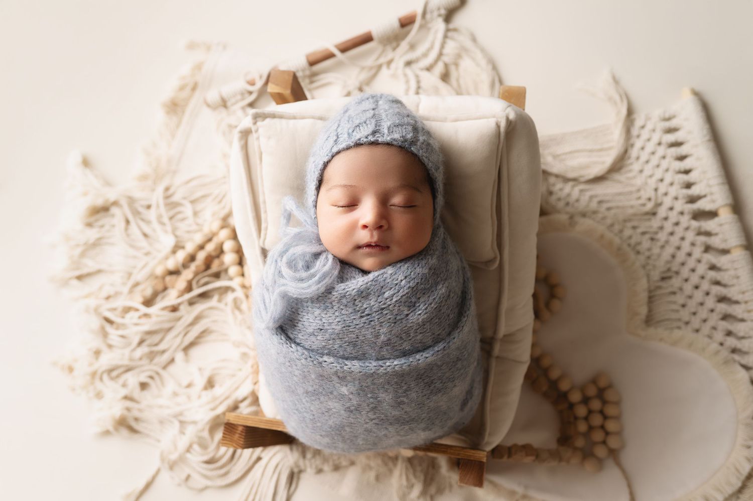 Professional newborn photography with baby wrapped in gray and beige knit blankets.