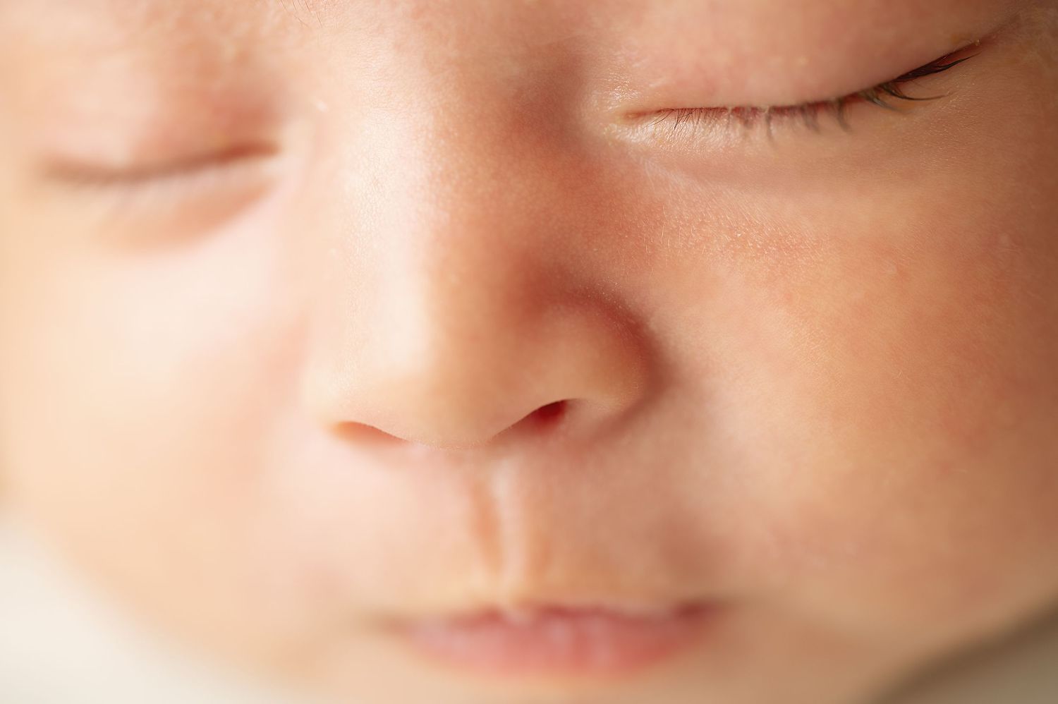 Extreme close-up of sleeping newborn's peaceful face showing delicate features.