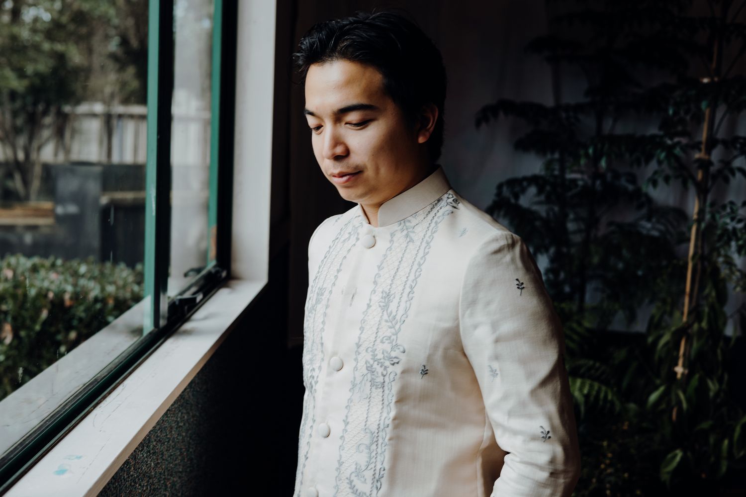 Elegant white Barong Tagalog with intricate embroidery detail near window.