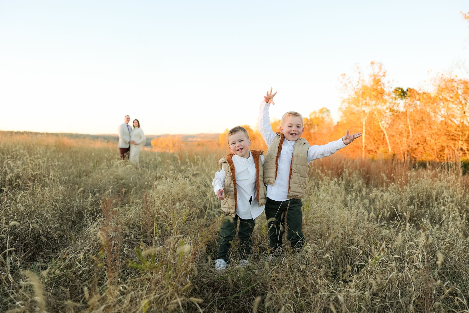 Family playing and jumping in a tall grass field during sunset.