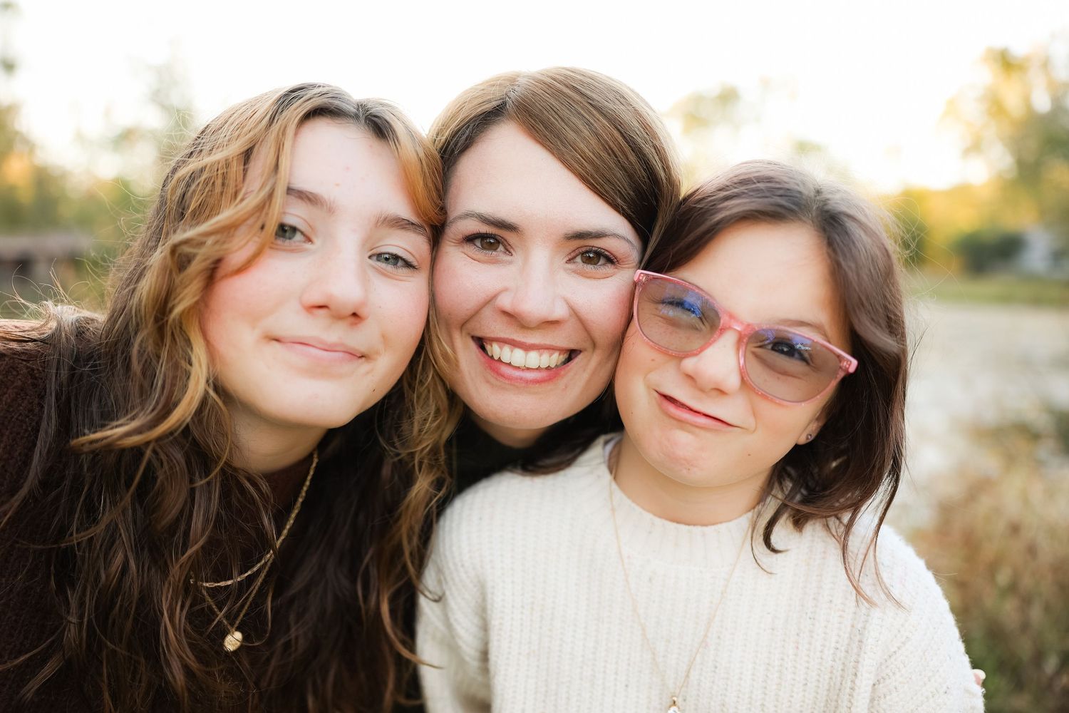 Mother and daughters pose close together during outdoor portrait session.