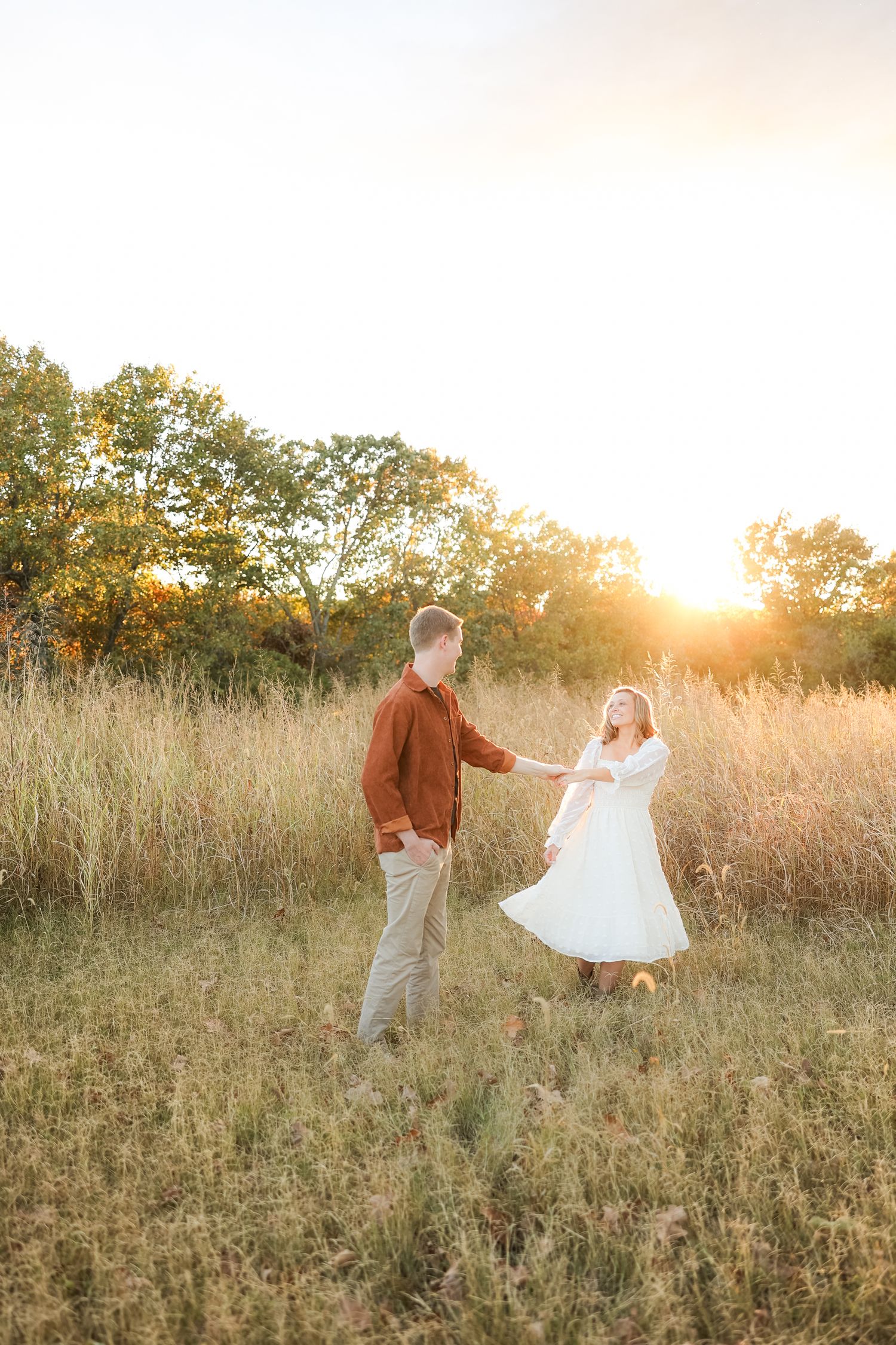 Couple dancing together in a sun-lit meadow during golden hour.