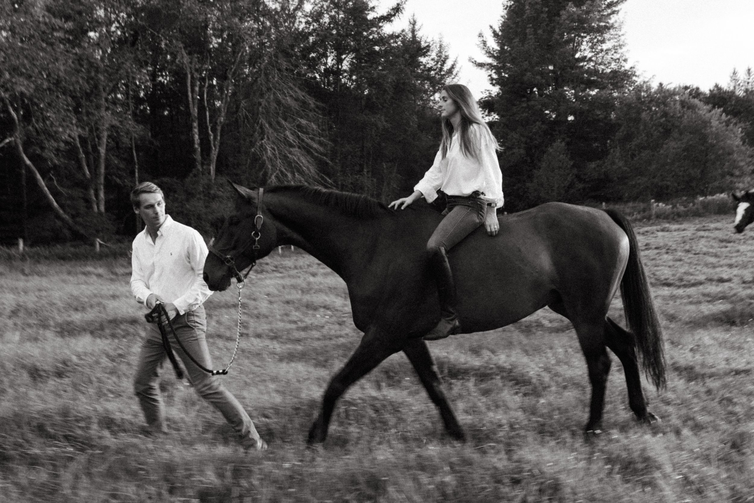 Casual countryside scene with horse riding and walking in black and white.