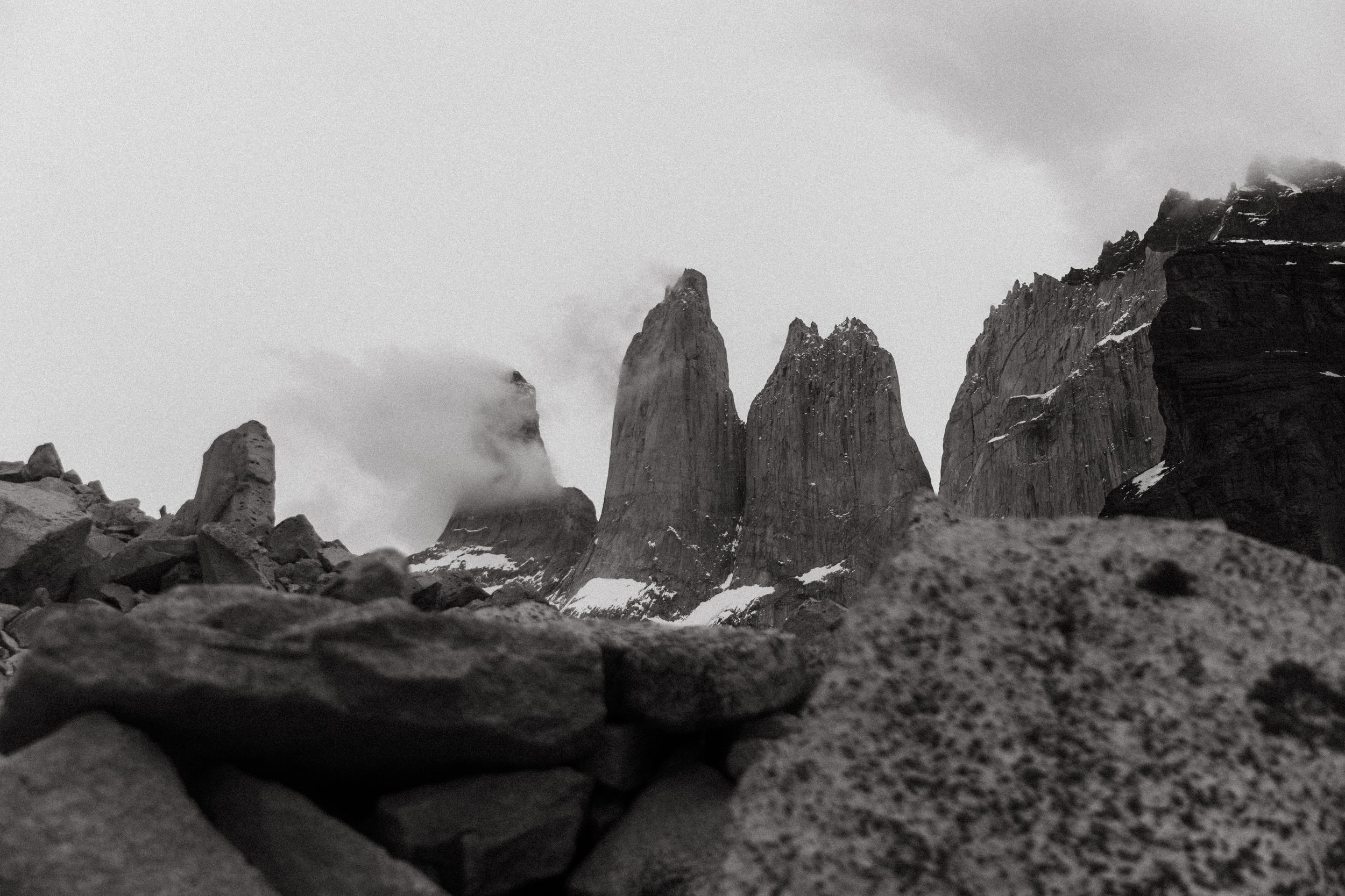 Dramatic black and white landscape of jagged mountain peaks emerging through misty clouds.