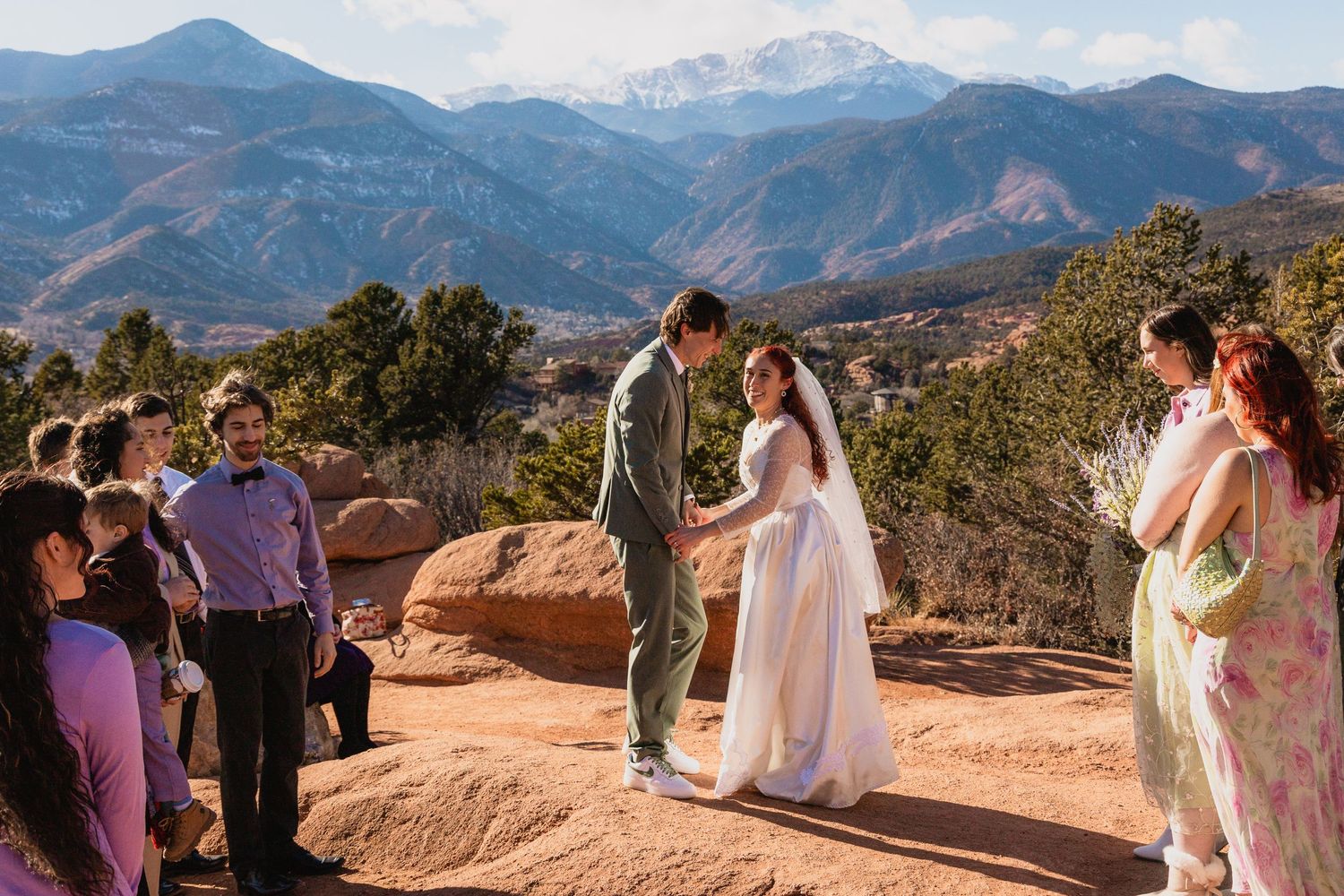 A wedding ceremony takes place on red rocks overlooking mountain peaks at Garden of the Gods in Colorado Springs.