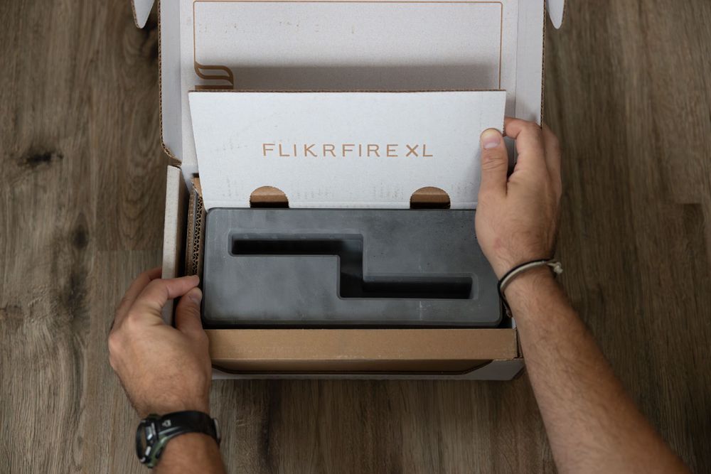 Hands unboxing a new Flickrfire XL product from premium packaging.