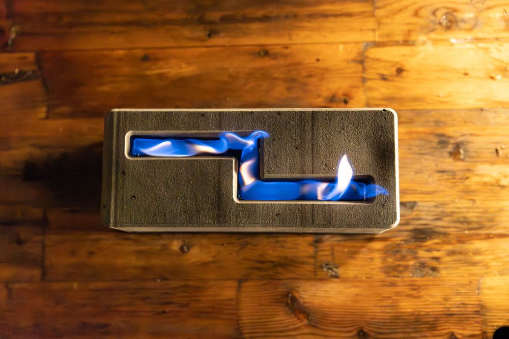 Tabletop fire pit with blue flames on wooden surface.
