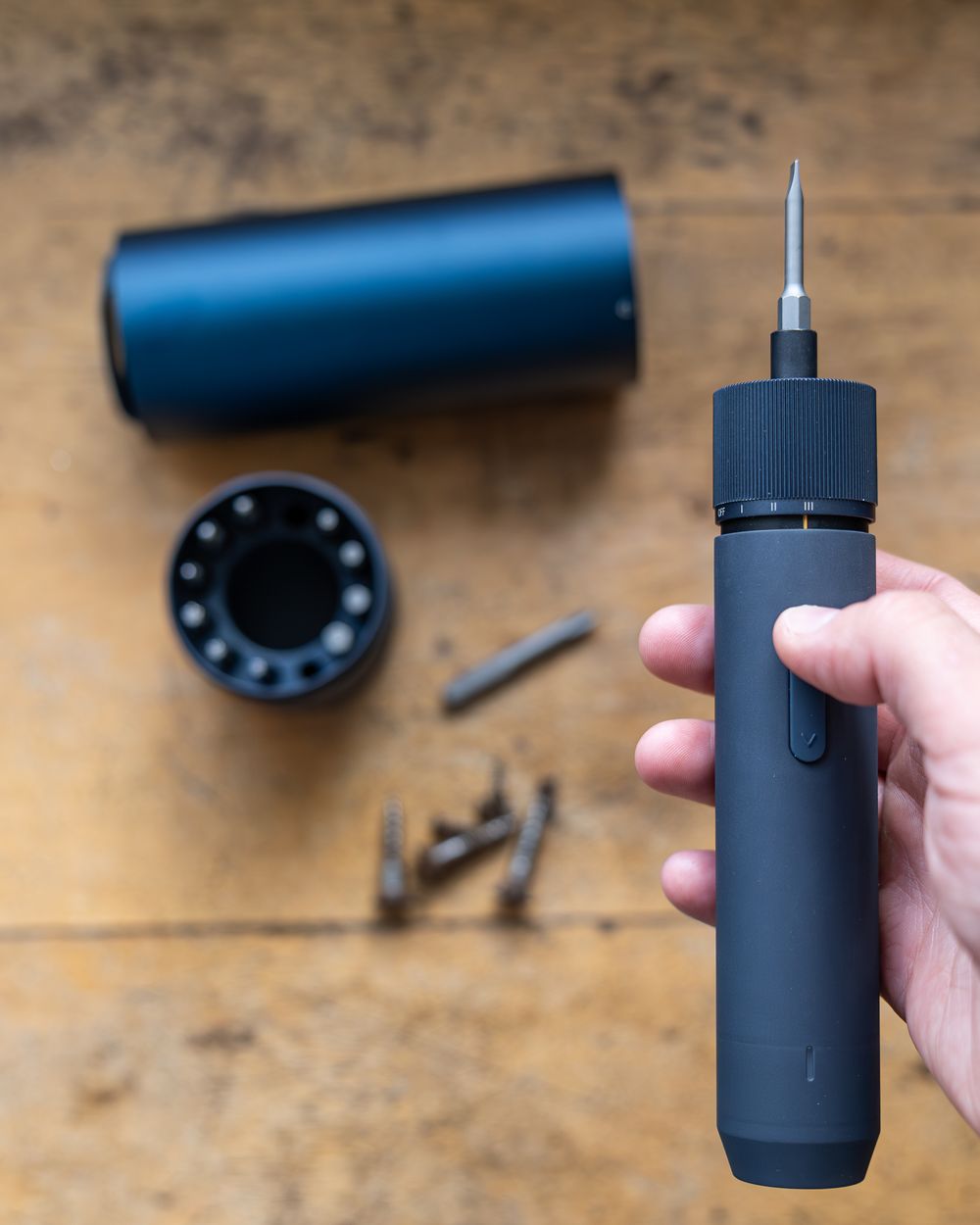 Black screwdriver tool components and parts on wooden surface.