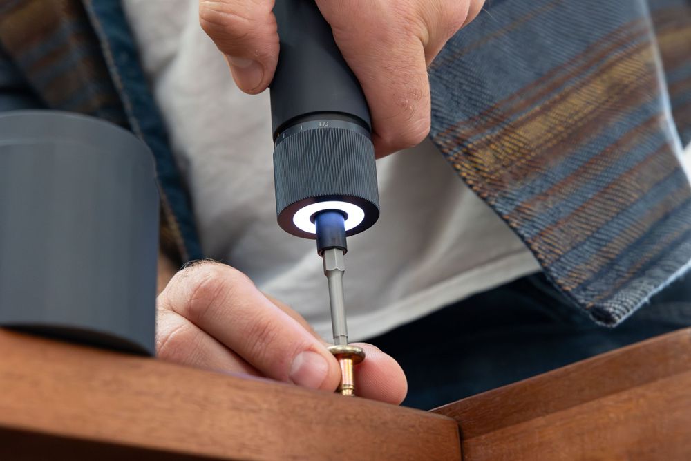 Close-up of electric screwdriver with blue light assembling furniture.