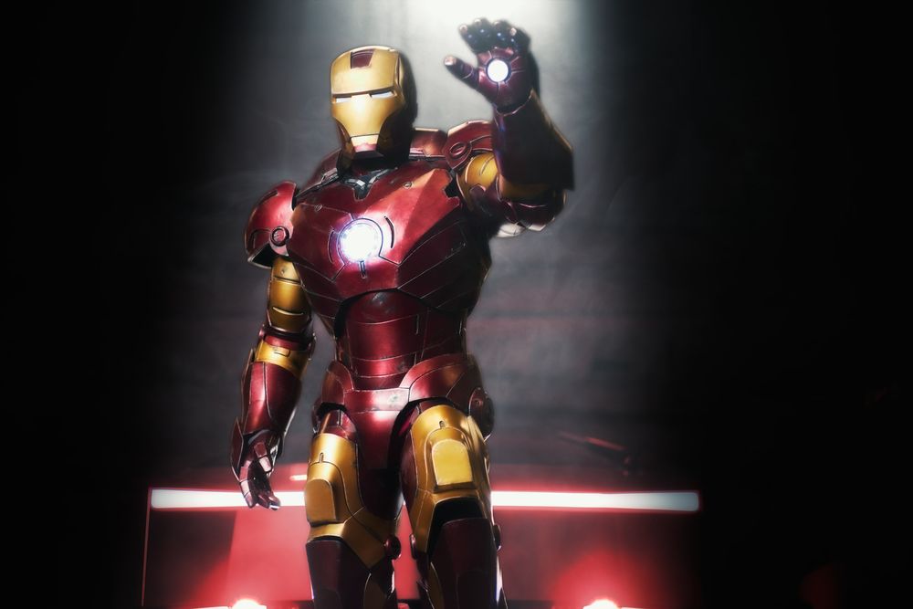 Iron Man action figure illuminated by dramatic red lighting stands in dynamic combat pose.