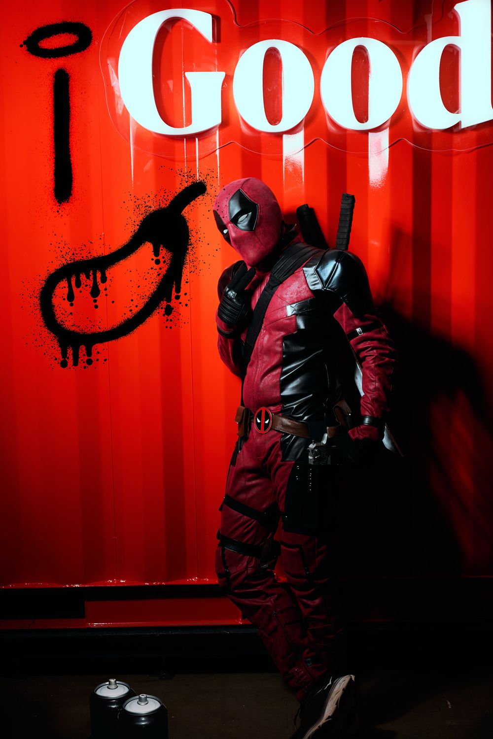 Cosplayer strikes dramatic poses against vibrant red wall with 'Good' lettering in moody urban photoshoot.