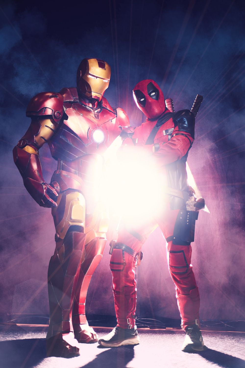 Iron Man and Deadpool action figures posing together with dramatic backlighting and smoke effects.