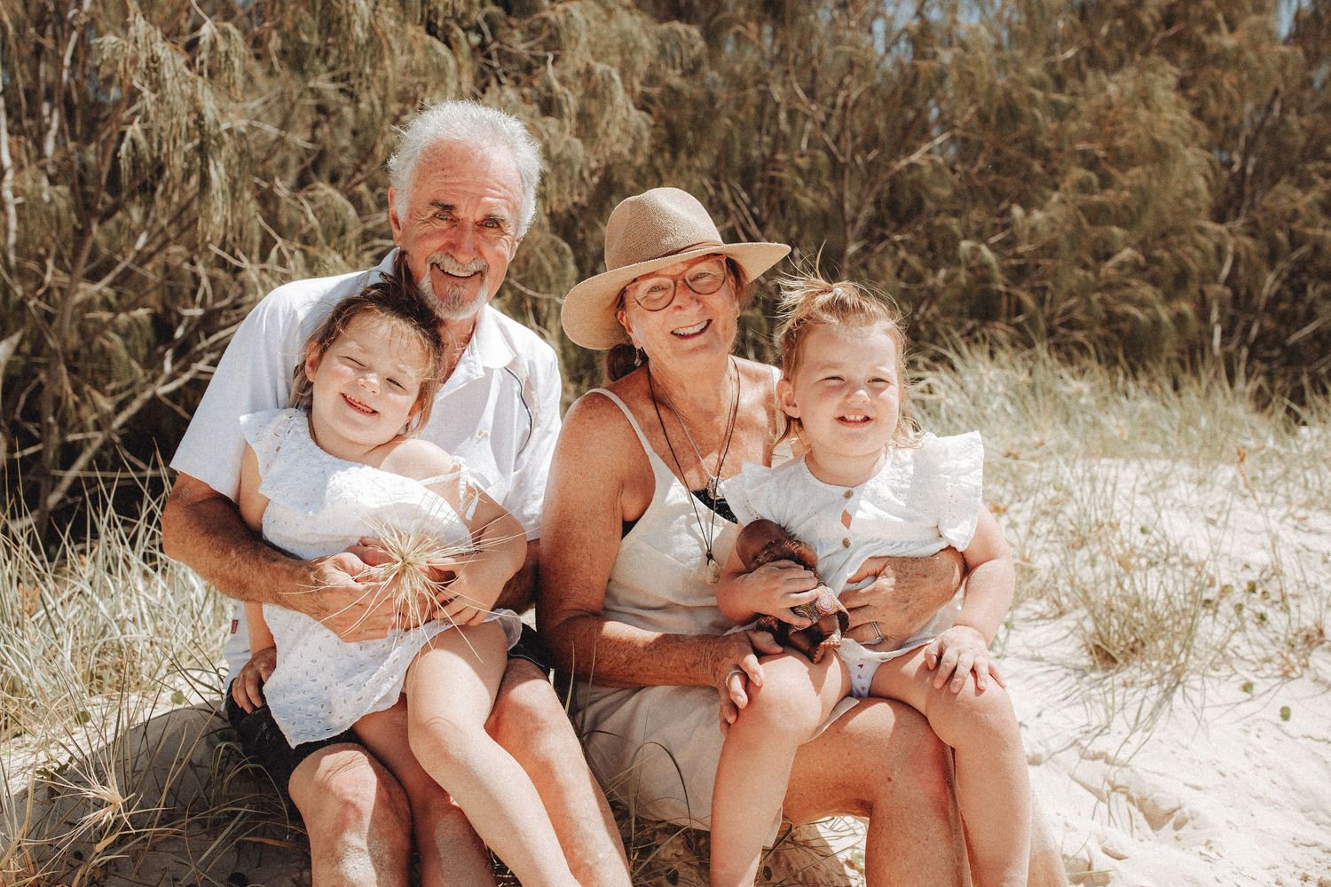 A happy family relaxes together outdoors on a sunny beach, sharing joyful moments in matching casual attire.