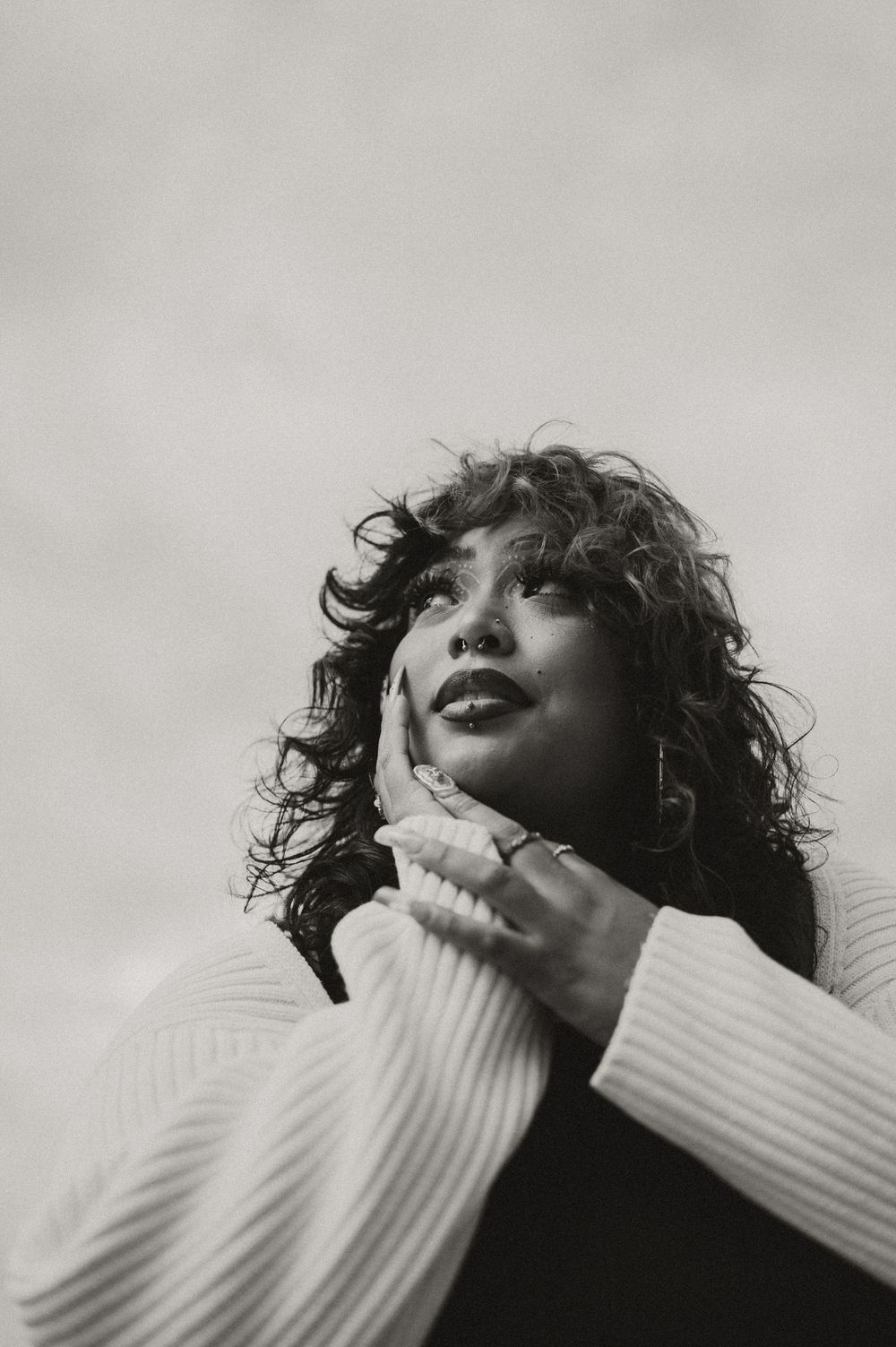 A black and white artistic portrait series showing dramatic poses with hands near face against a light grey background.