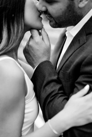 man kissing fiance with hand on her chin in black and white