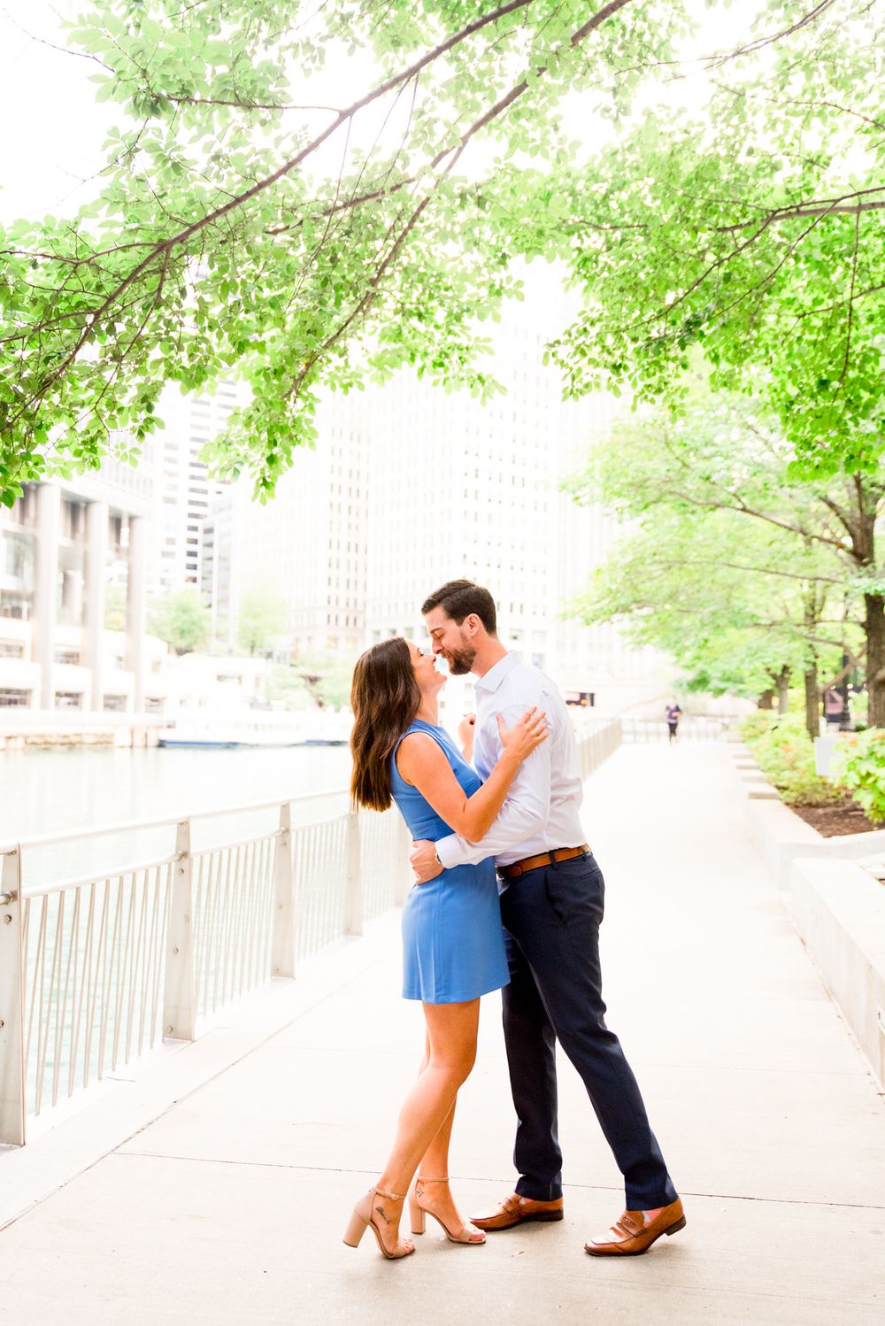 woman in blue dress twirling around with her fiance in white shirt for sunrise chicago engagement pictures