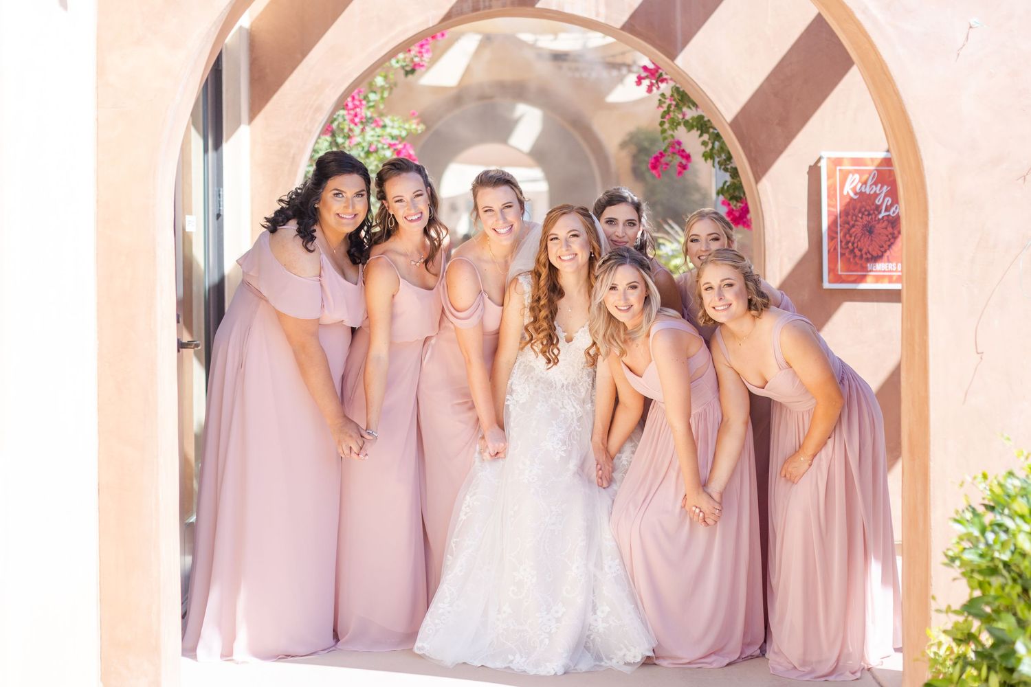 Best bridesmaids pose huddled together in archway