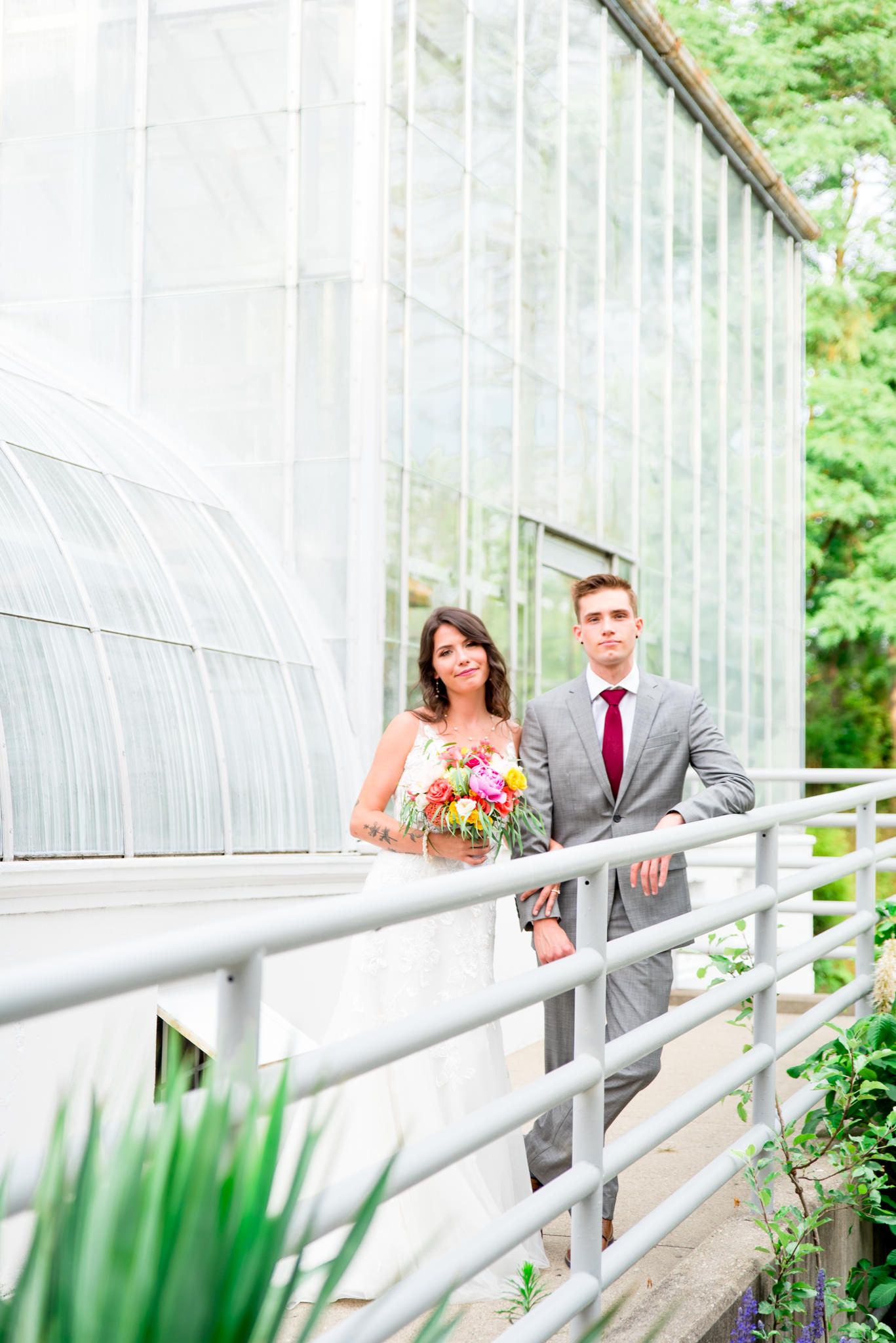 bride and groom stare into the camera in front of Krohn Conservatory for their summer wedding