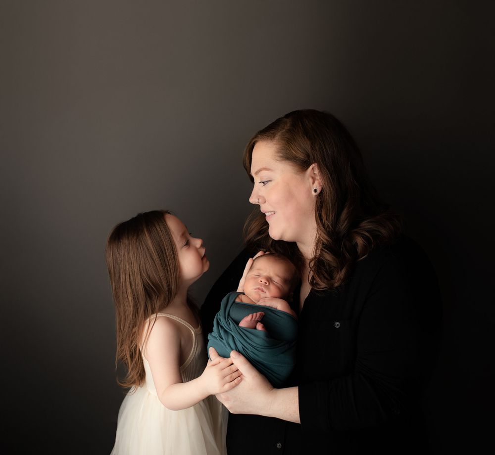 Professional newborn photo with mom and sister