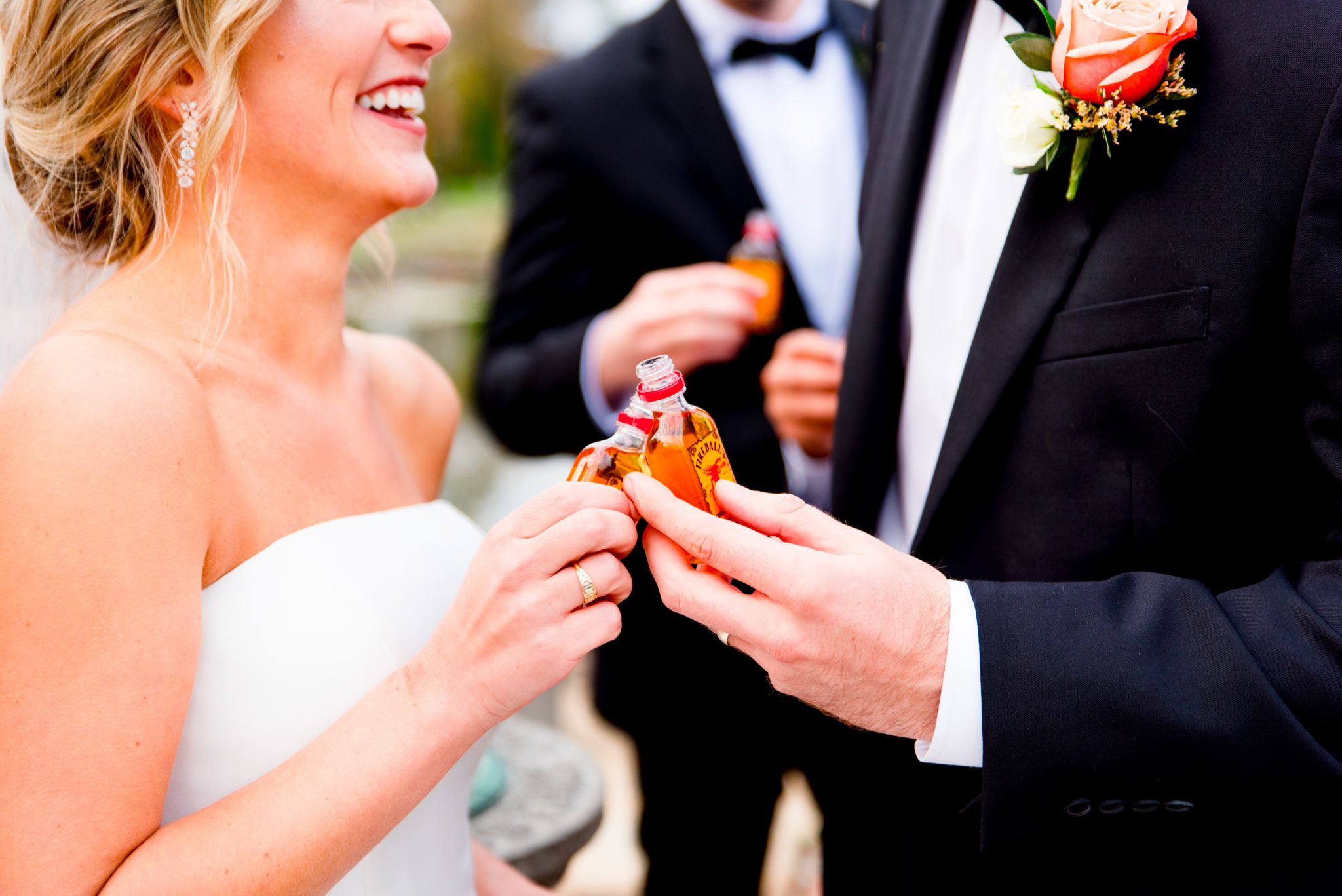 bride and groom clinking shot bottles of Fireball