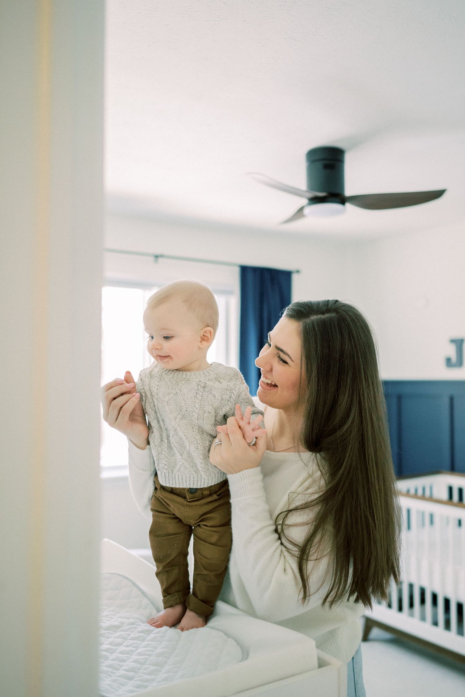 A tender moment shared in a modern nursery with white walls and navy blue accents.