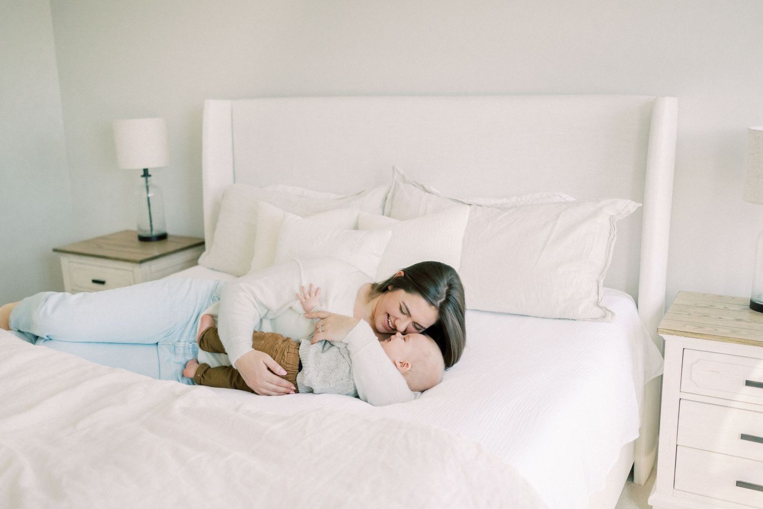 Peaceful nap time moment on white bedding in bright bedroom.