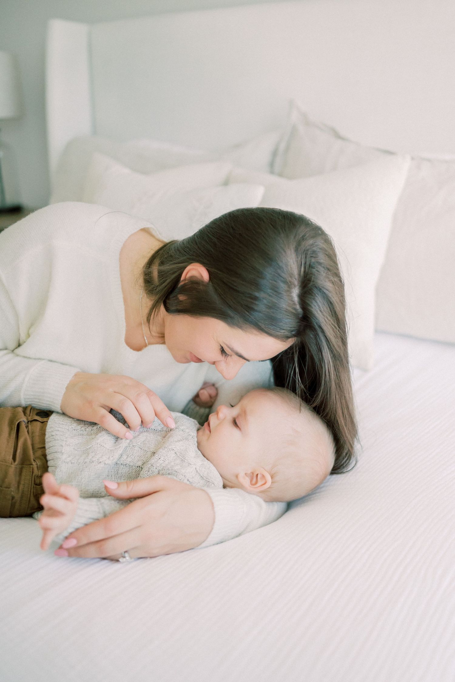 Intimate bonding moment between parent and baby on white bedding.