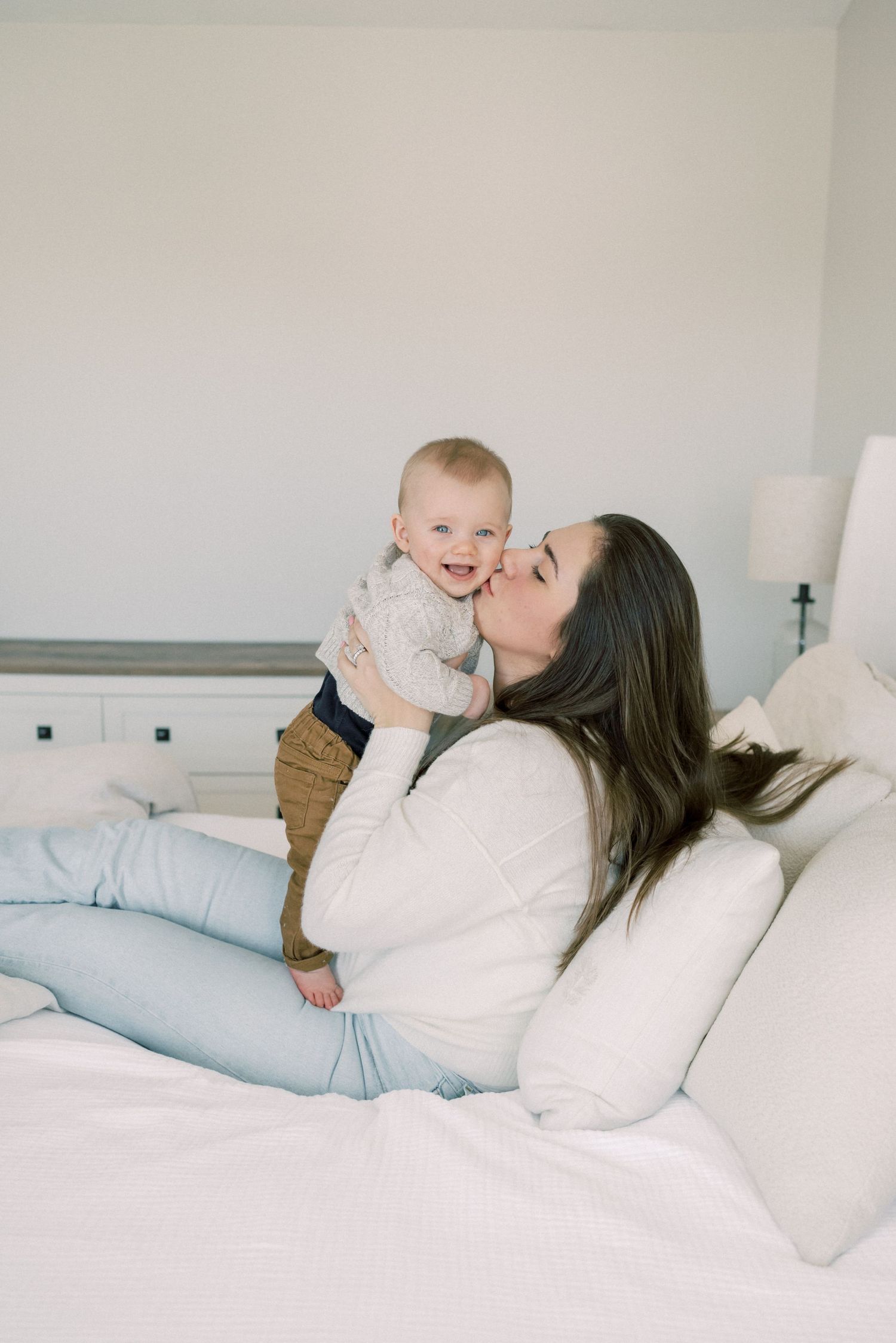 A tender moment between parent and baby relaxing together on a white bed.