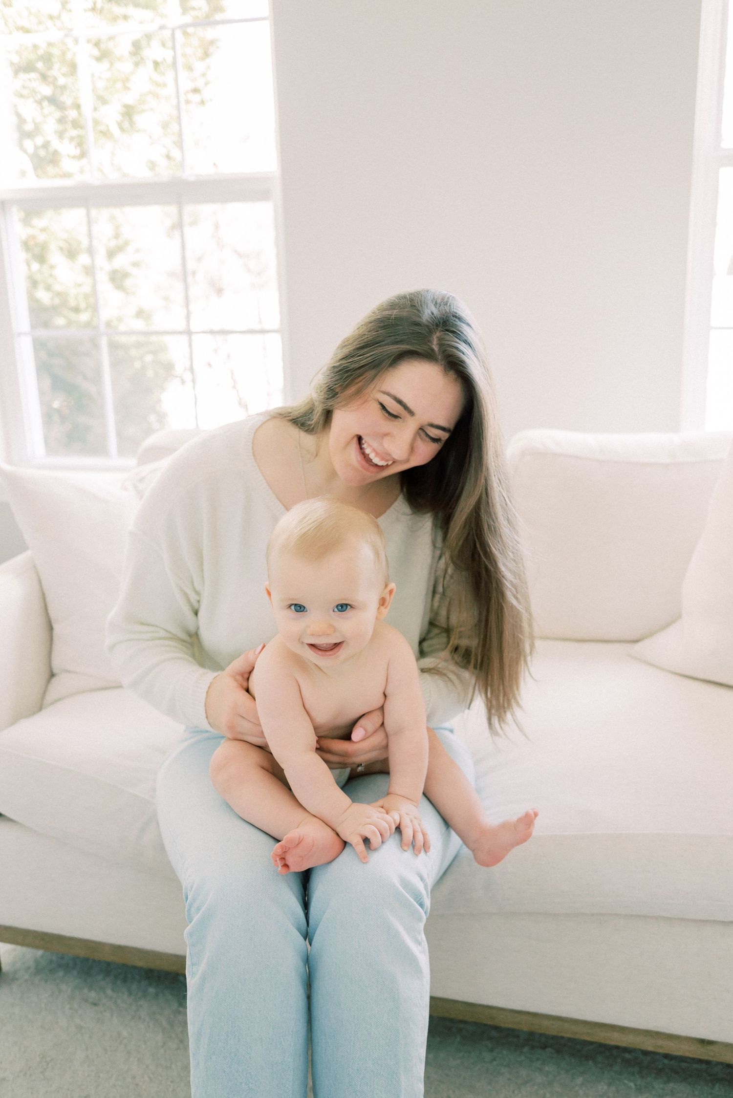 A tender moment shared between parent and baby on a white couch.